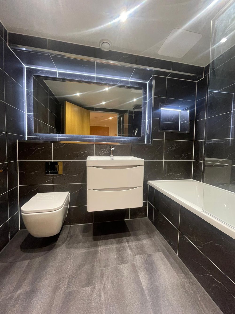 Dark marble effect bathroom with a lit mirror
