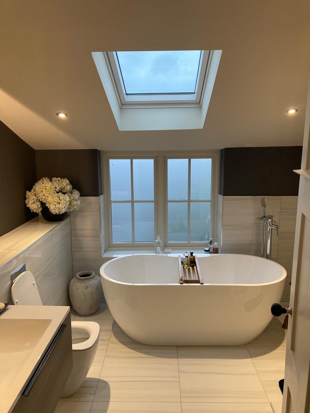 Freestanding bath under a window with wall mounted taps