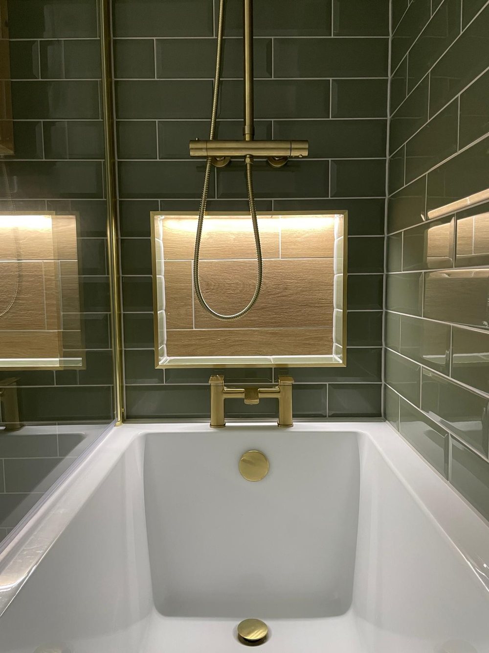 Green metro tiled shower with a brass shower set