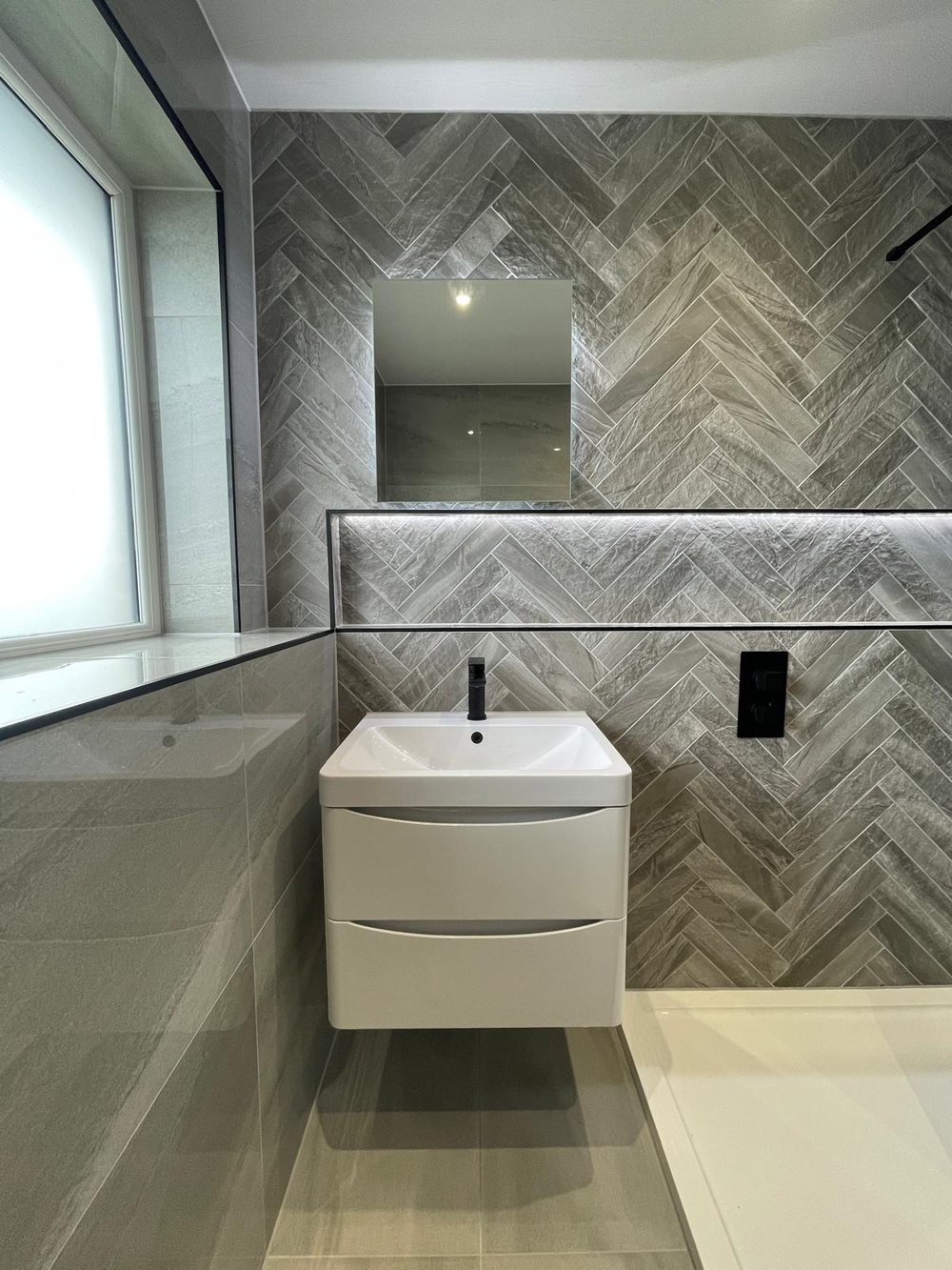 Herringbone feature tiles behind a white vanity