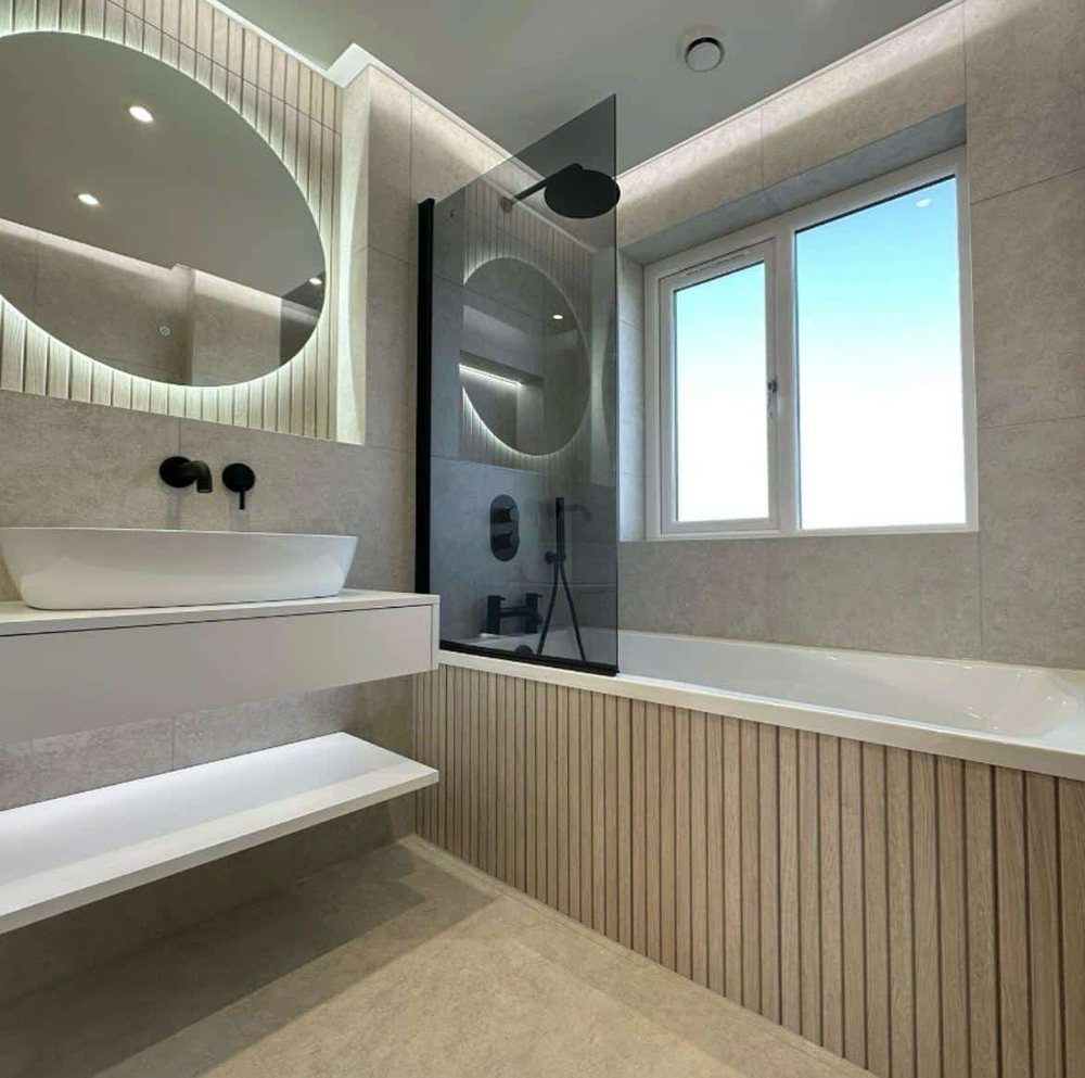 Oak panelled bath under a window with a round mirror