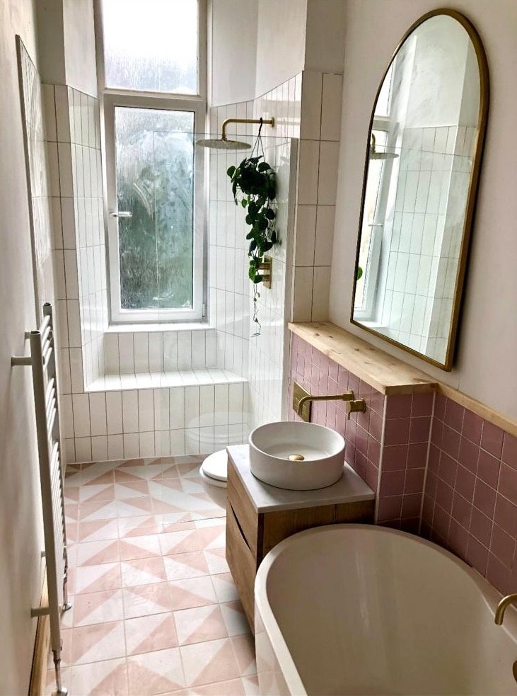 Stone vessel basin with a brass wall tap on pink tiles