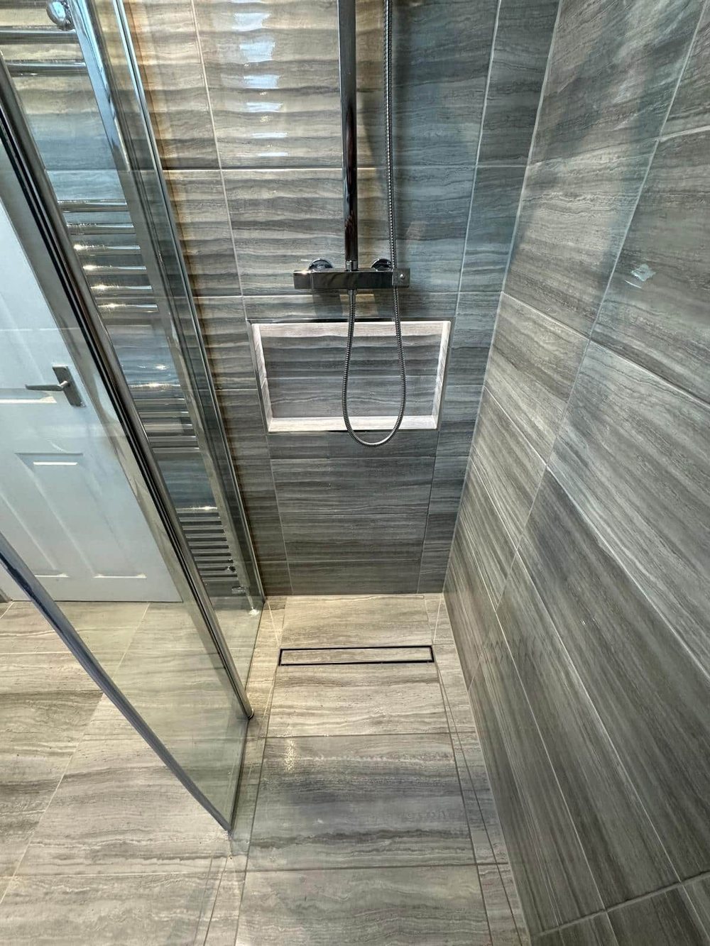 Walk-in shower with wood effect tiles and a linear drain