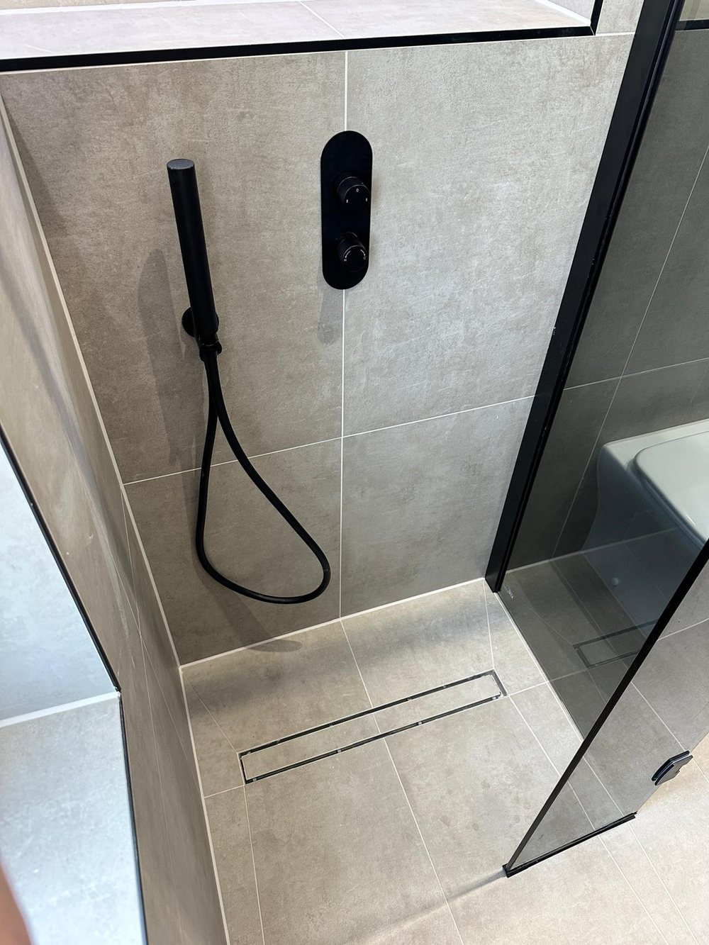 Wet room with black shower fittings and a glass screen
